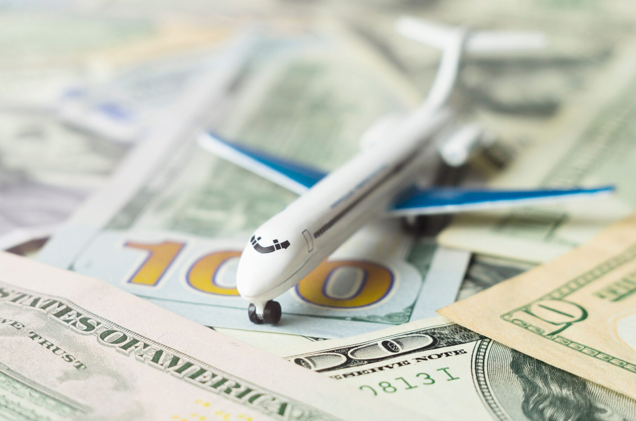 The ACI Guide to Airport Economic Regulation sits atop scattered U.S. $100 and $20 bills, representing the financial aspects of airport operations and travel expenses.