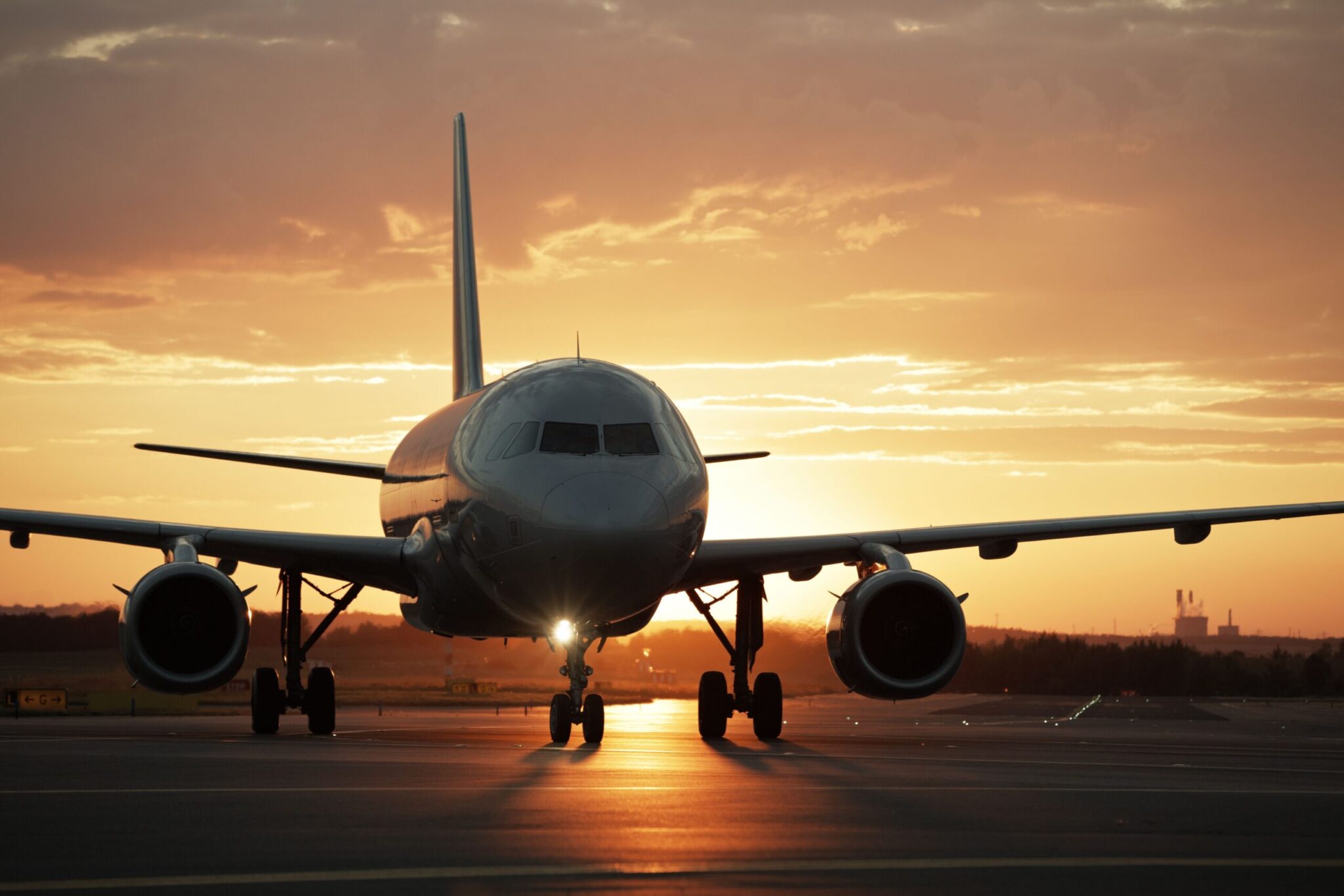 A commercial airplane taxis on a runway at sunset, golden light illuminating the scene—a striking moment captured in The Evolution of Airports: Flightpath to 2050.