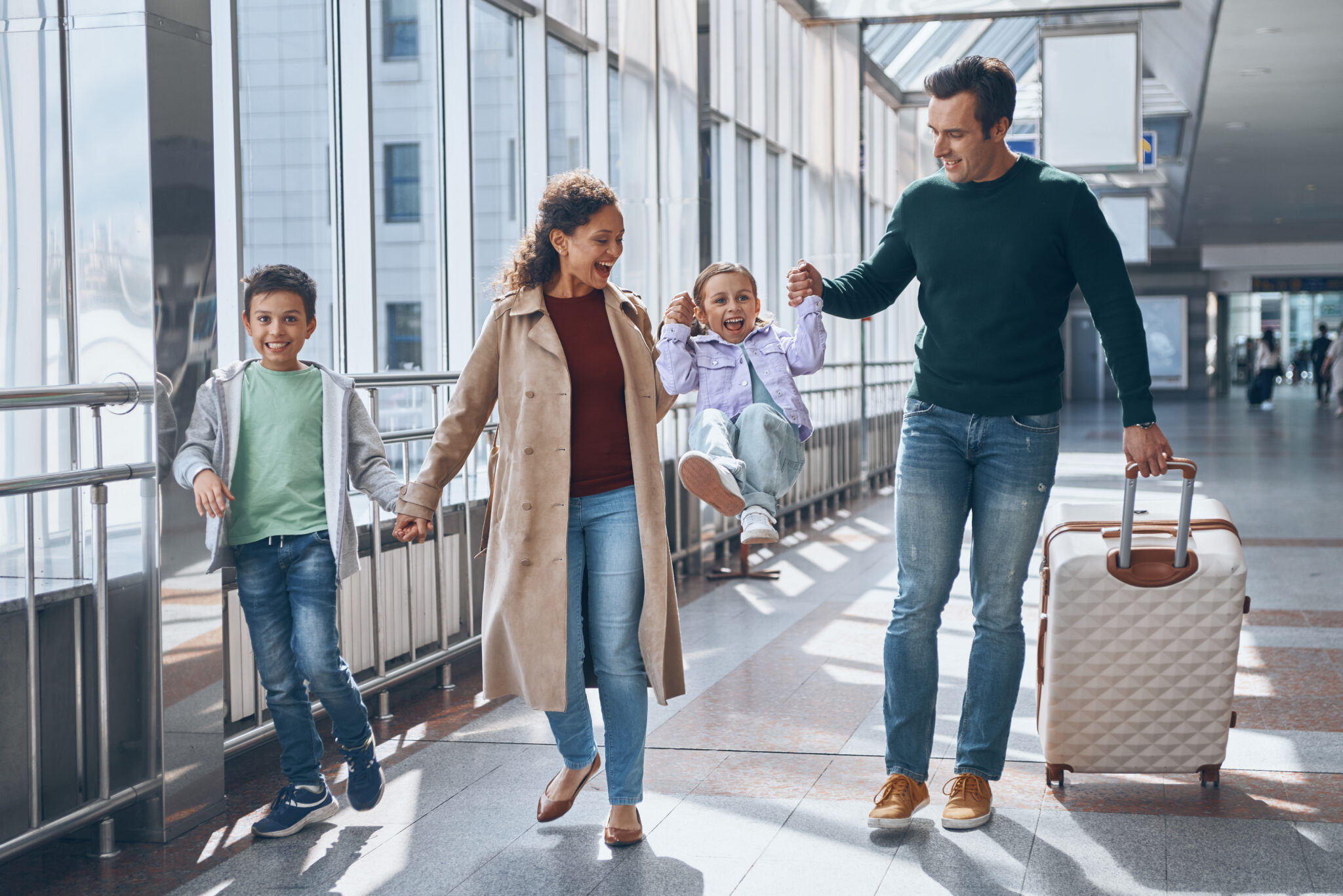 A smiling family of four walks through an airport, enjoying their journey—an example of the seamless travel experience you can create with Mastering Airport CX: Trainings and Strategies for Success.